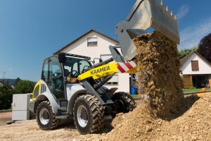Kramer 8075 im Einsatz mit Breitreifen und Greiferschaufel